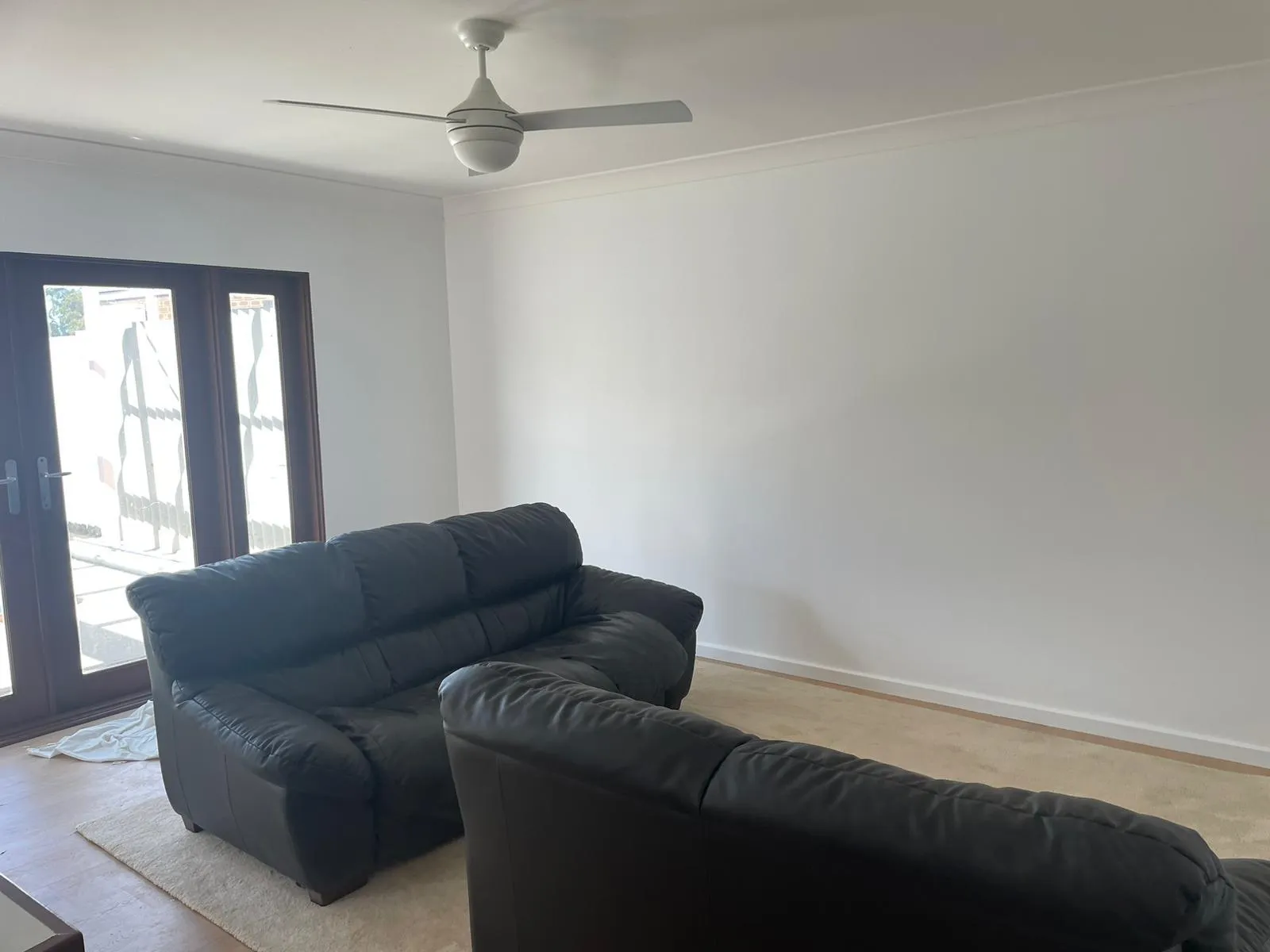 Bright living room with ceiling fan and sliding glass doors
